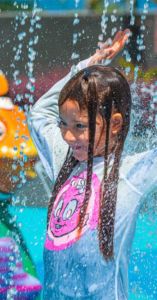 Niña feliz jugando en un splash pad construido por Amusement Logic