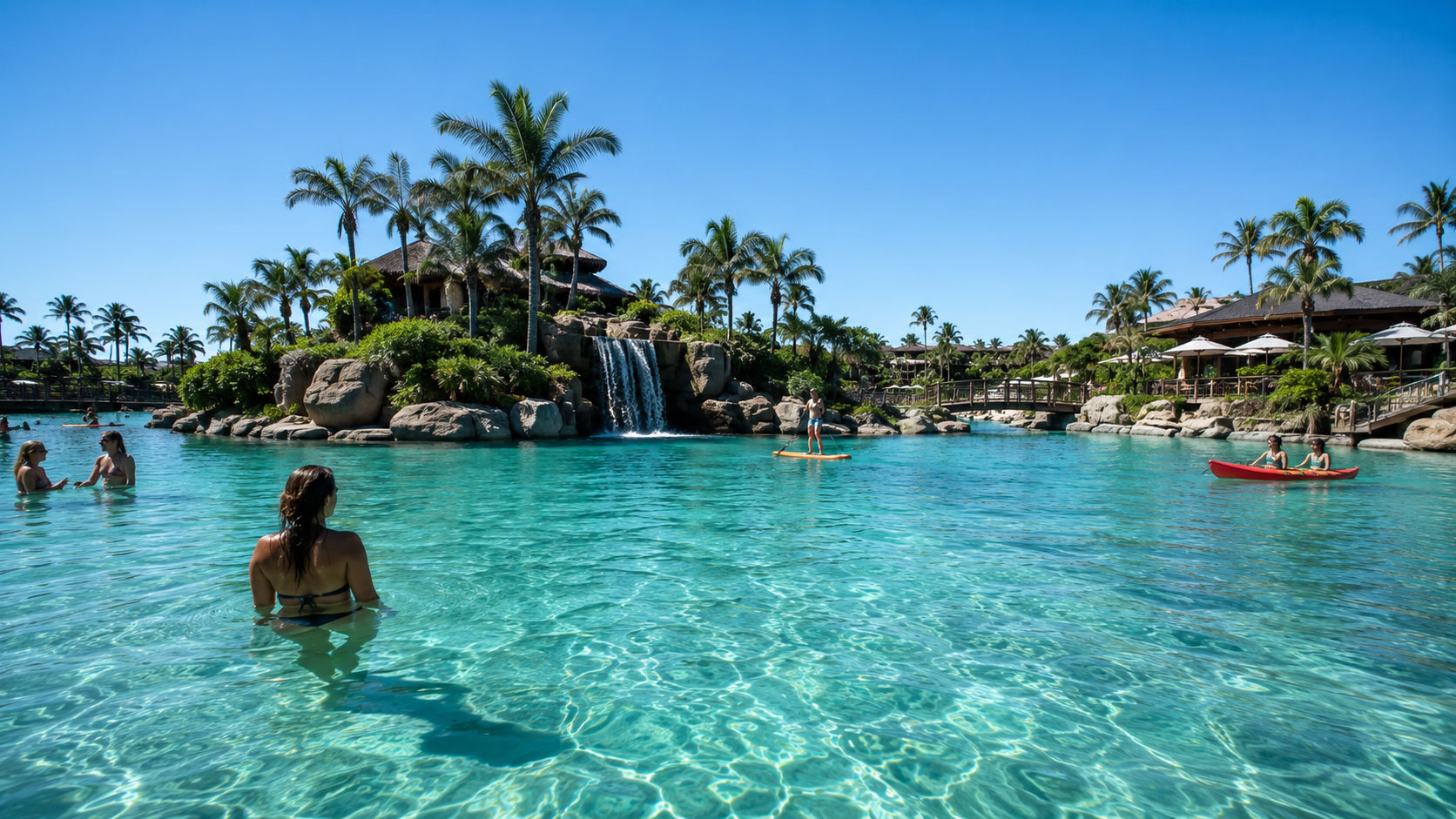 Bañistas en agua turquesa poco profunda junto a una isla con cascada y palmeras.